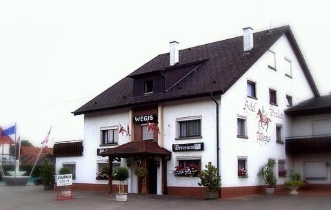 ein großes weißes Gebäude mit schwarzem Dach in der Unterkunft Hotel Wegis Garni in Bermatingen