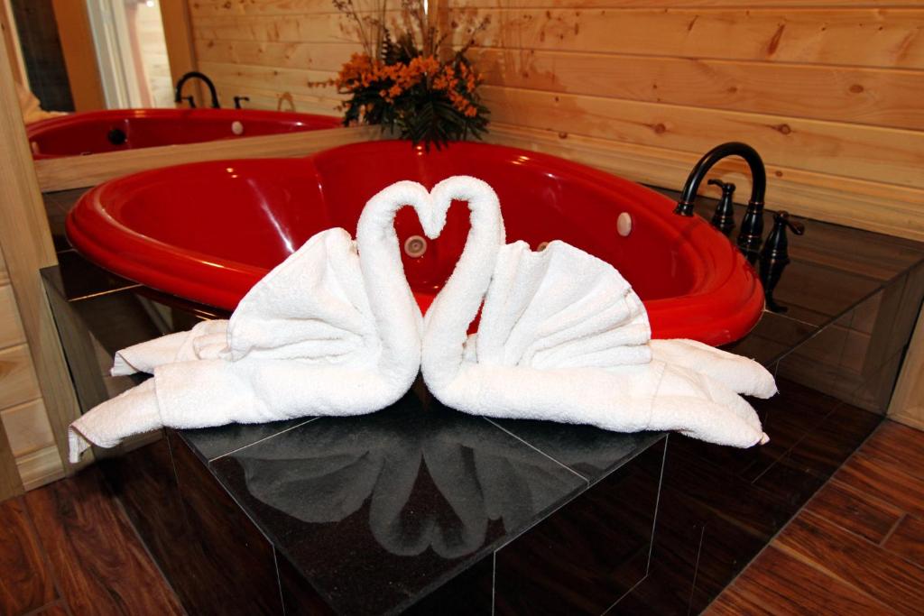 dos cisnes sentados en una bañera roja en un baño en Endless Mountain Dreams en Gatlinburg