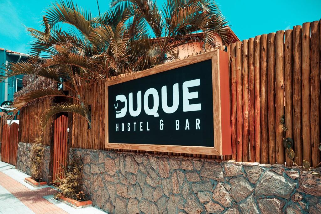 una señal para un hotel y un bar en una valla en Duque Hostel en Florianópolis