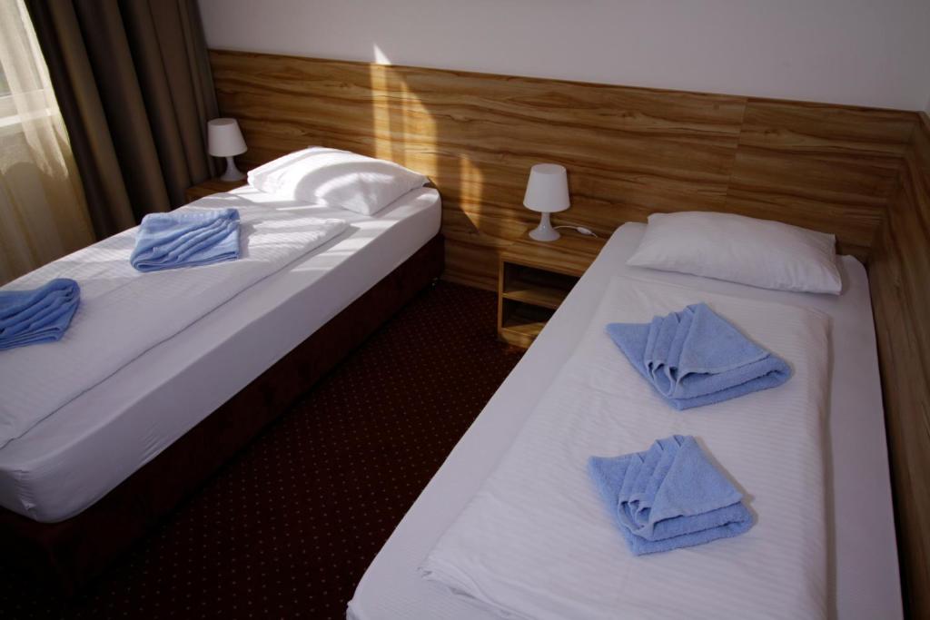 two beds in a hotel room with blue towels on them at Aviator Garni Hotel Bratislava in Bratislava