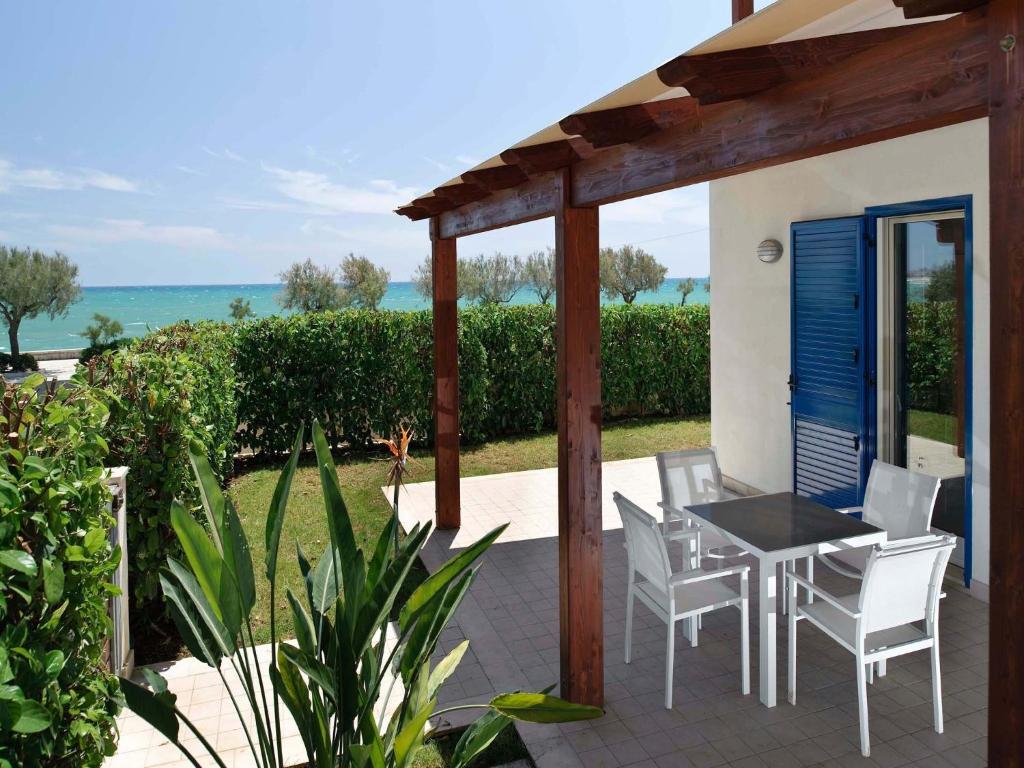 een patio met een tafel en stoelen en de oceaan bij Dolce Mare in Marina di Modica