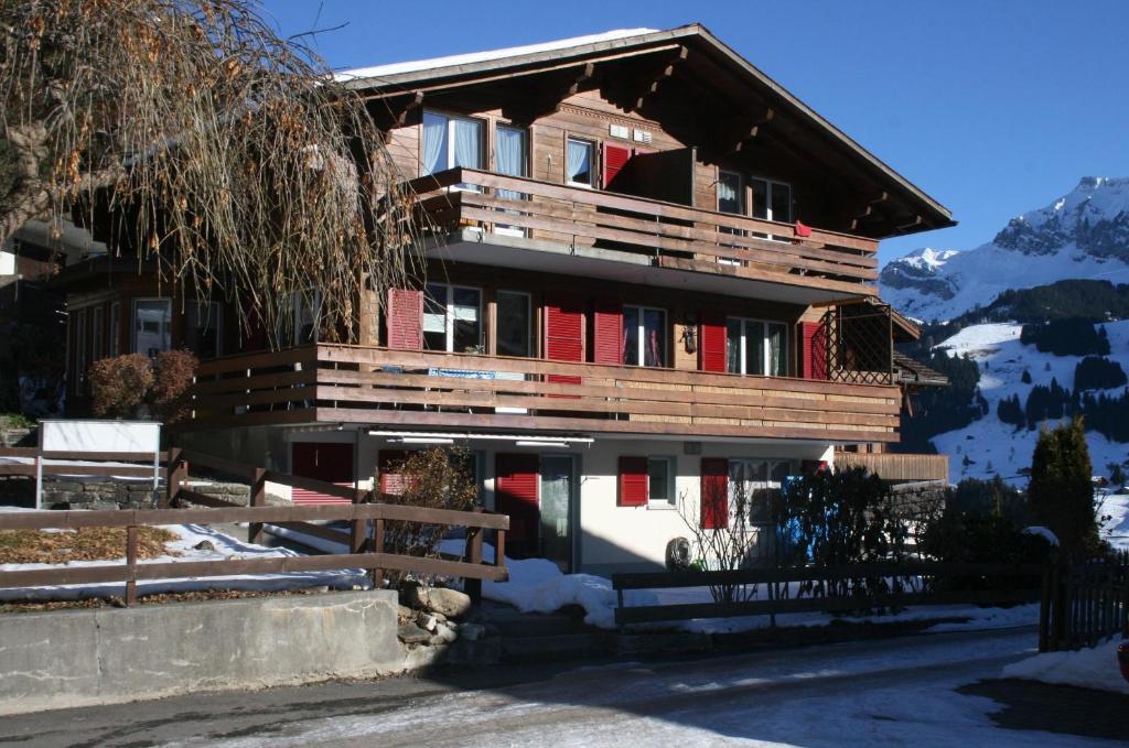 ein großes Holzgebäude mit roten Türen im Schnee in der Unterkunft Chalet Silky in Adelboden