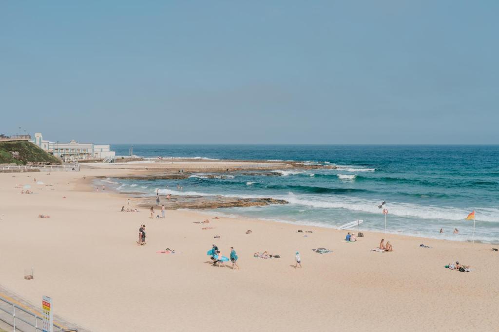 a group of people on a beach near the ocean at Novotel Newcastle Beach in Newcastle