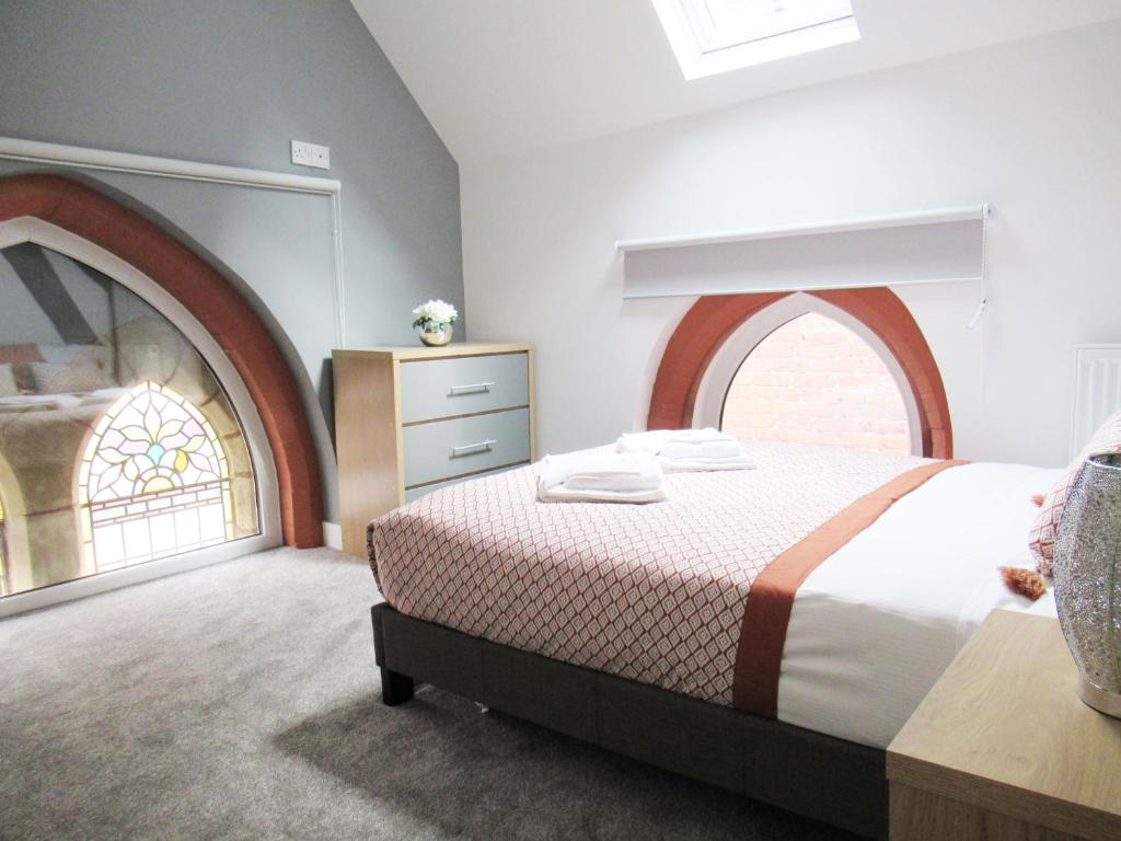 a bedroom with a bed and an arched window at Emmanuel Church Apartments in Warrington
