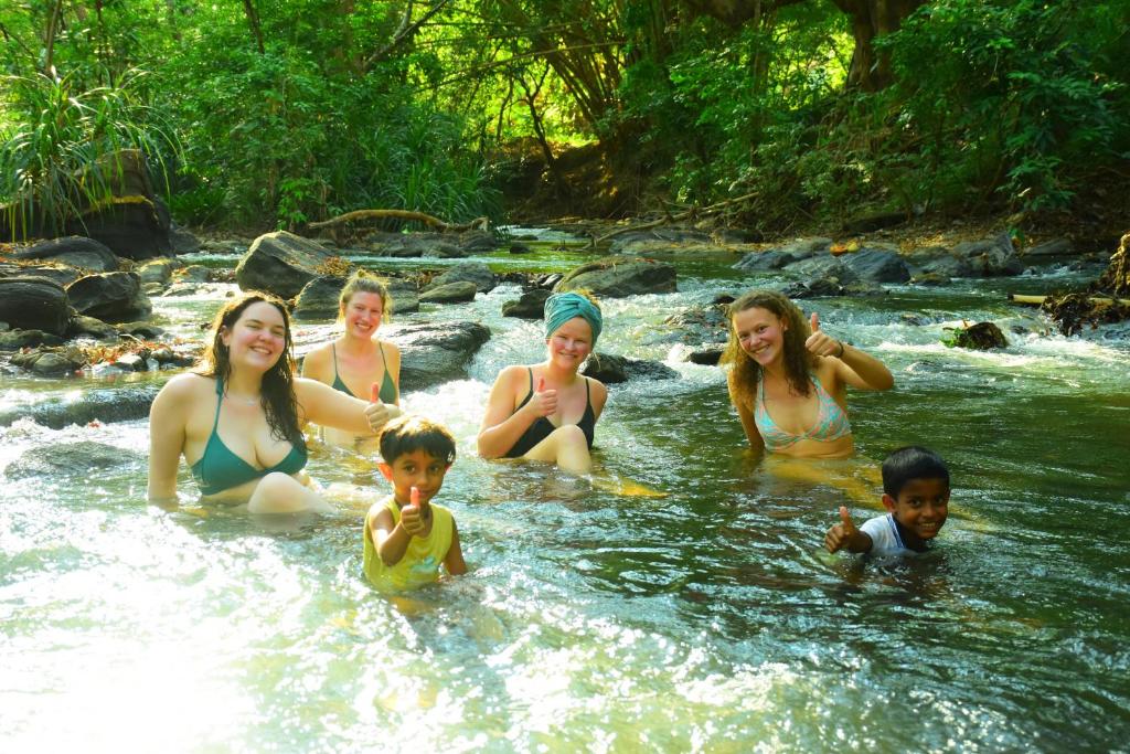 a group of women and children sitting in a river at Silent River Cottage in Udawalawe