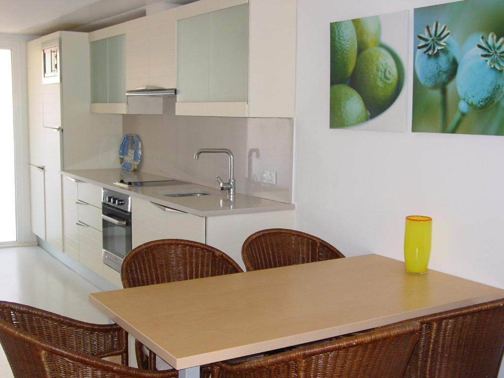 uma cozinha com uma mesa de madeira e cadeiras em Apartamentos Rodamar em L'Estartit