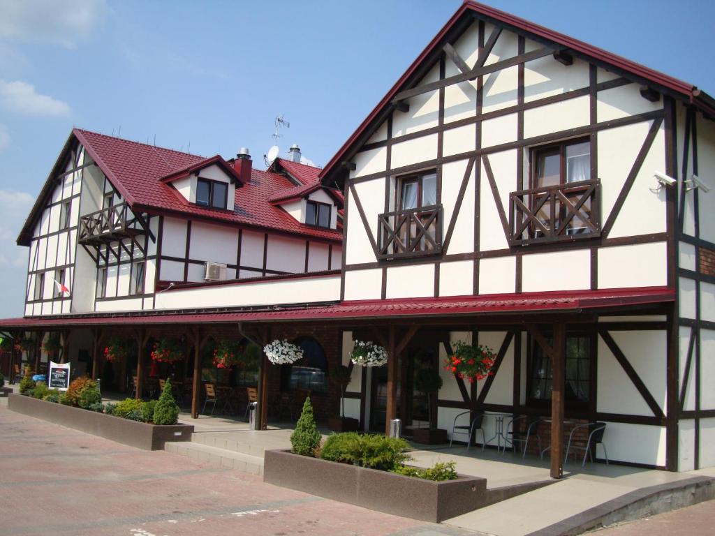 a black and white building with red roof at Zajazd Harasówka in Gniewkowo