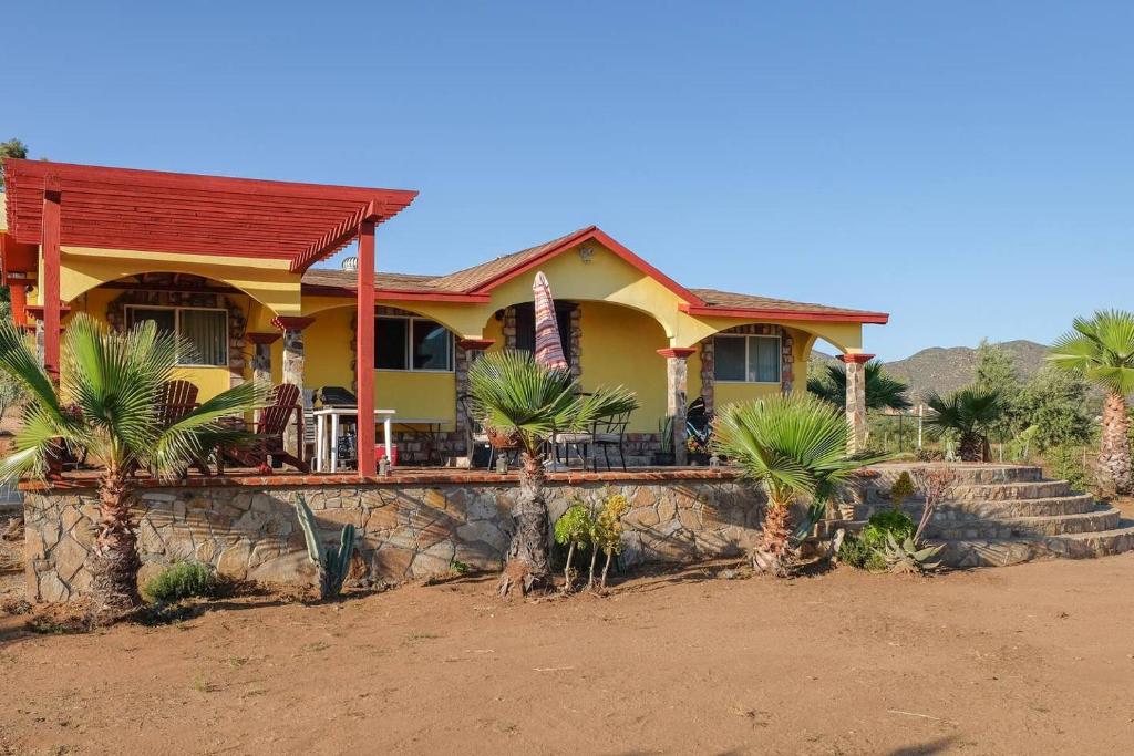 a yellow house with palm trees in front of it at El Rincón Del Valle en la Ruta Del Vino in Valle de Guadalupe