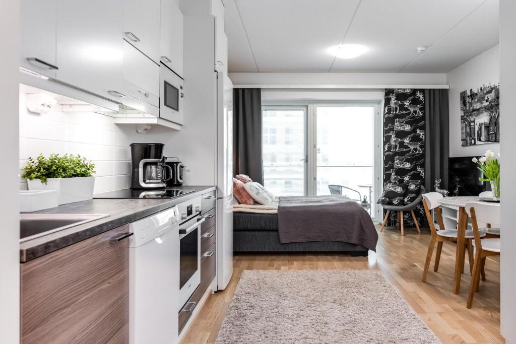 a kitchen and living room with a bed in the background at Trendy Homes Oulu Rautatienkatu in Oulu