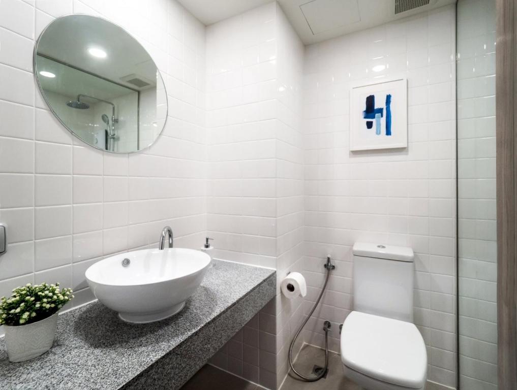 A clean tiled bathroom with vessel sink, toilet and shower enclosure.