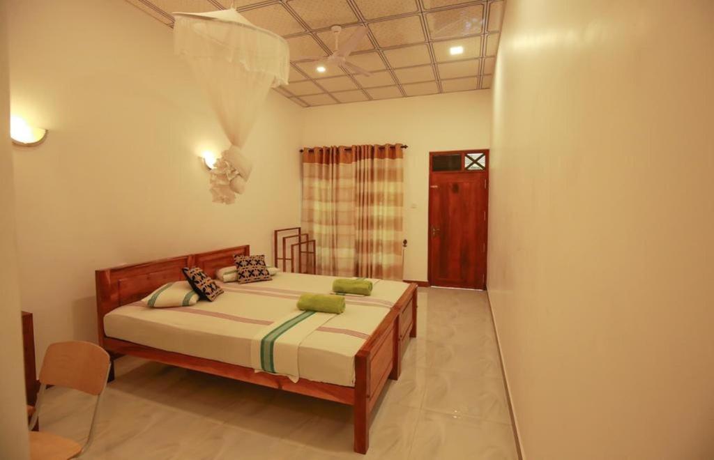 Schlafzimmer mit einem Bett und einem Fenster in der Unterkunft Julia Safari Inn in Tissamaharama