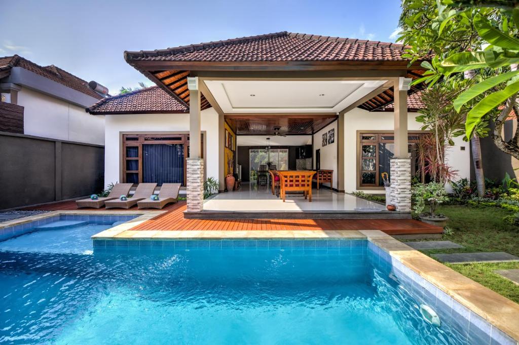 a swimming pool in front of a house at Gracia Bali Villas & Apartment in Seminyak
