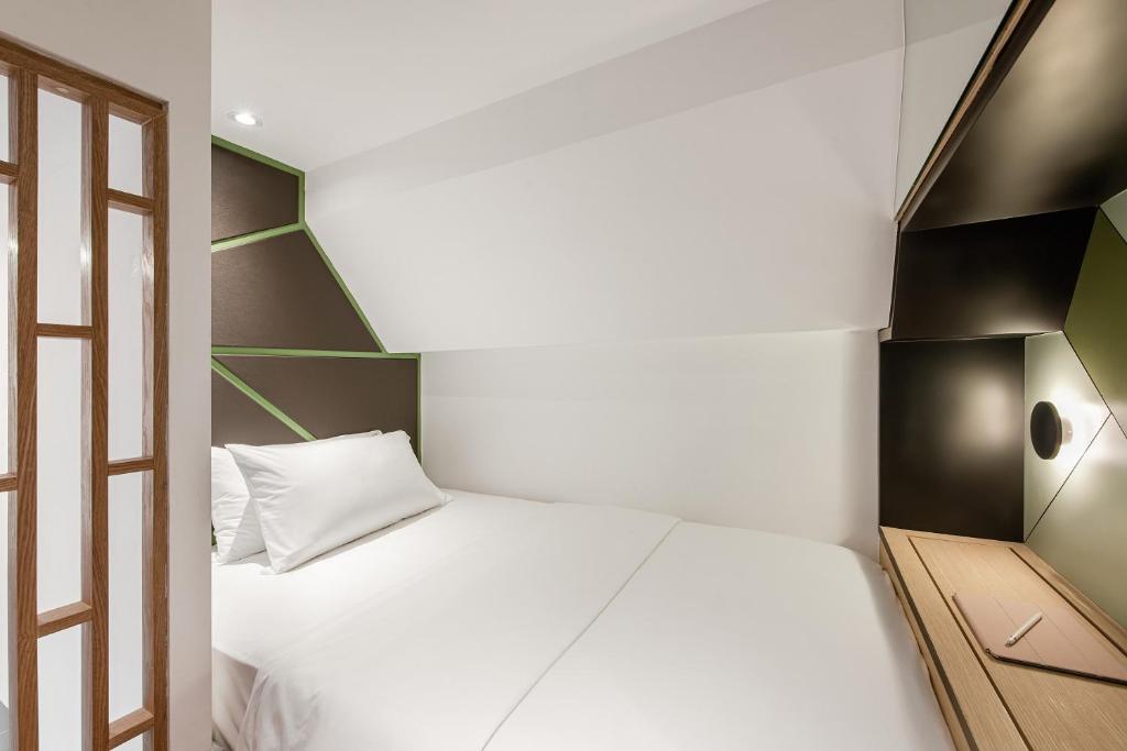 a small bedroom with a white bed and a window at Komune Living in Kuala Lumpur