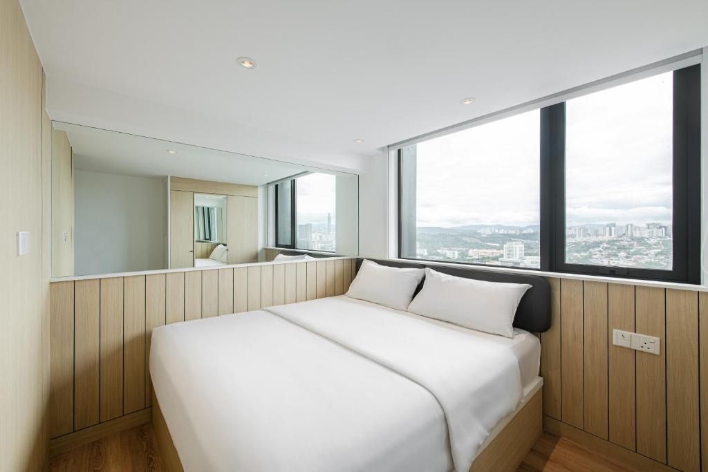 a white bed in a room with a large window at Komune Living in Kuala Lumpur