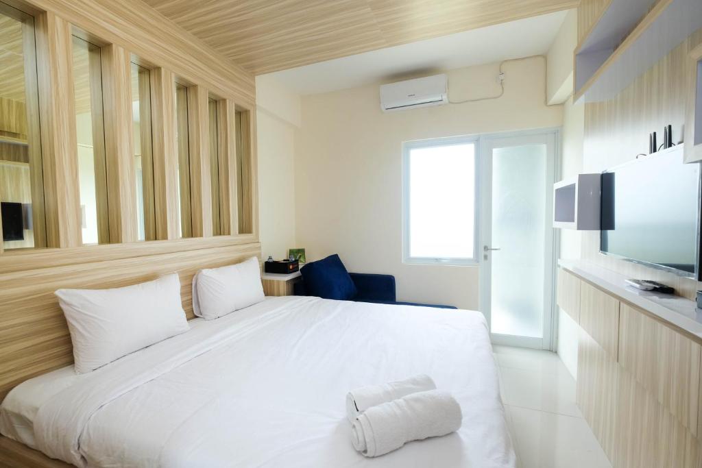 a bedroom with a white bed and a television at Elegant Studio Apartment at Bogorienze By Travelio in Bogor