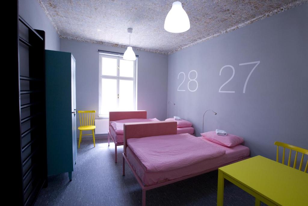 a room with two beds and a table and a window at Hostel U Zlatého kohouta in Kroměříž