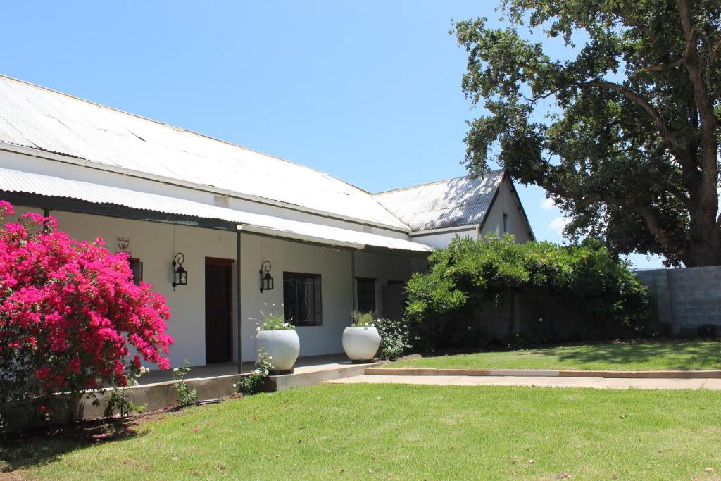 una casa con flores rosas en un patio en Rooikraal Farm Guesthouse and dam, en Prince Alfreds Hamlet