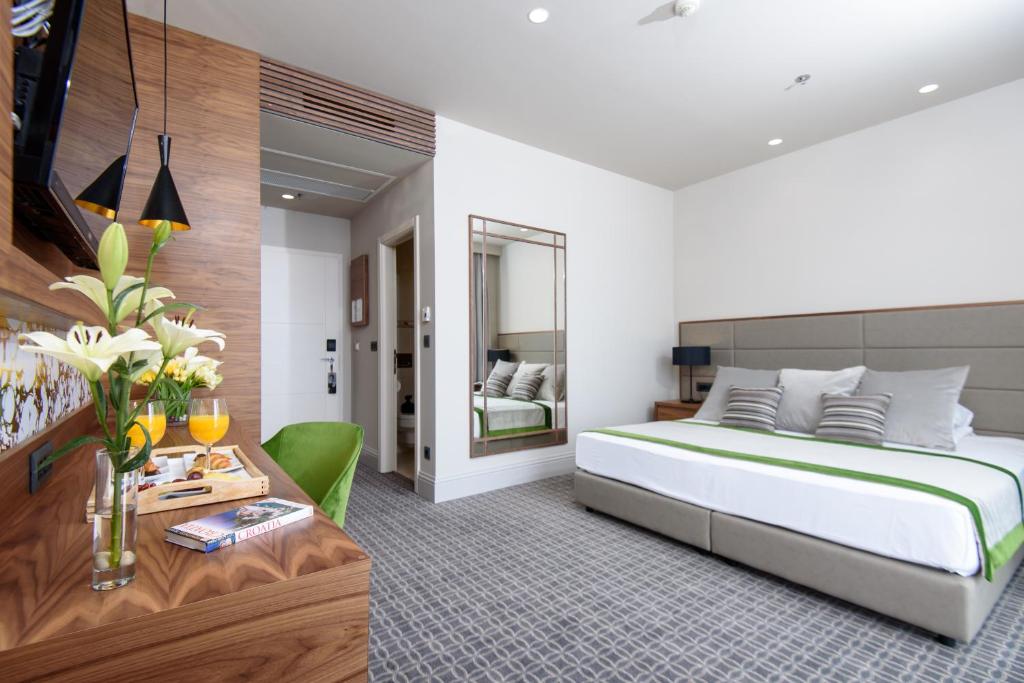 a bedroom with a king sized bed and a desk at Royal Neptun Hotel in Dubrovnik