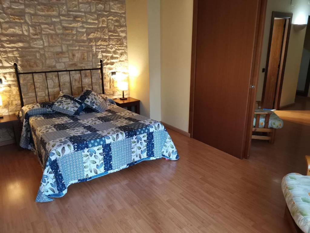 a bedroom with a bed and a stone wall at Hostal del Senglar in Espluga de Francolí