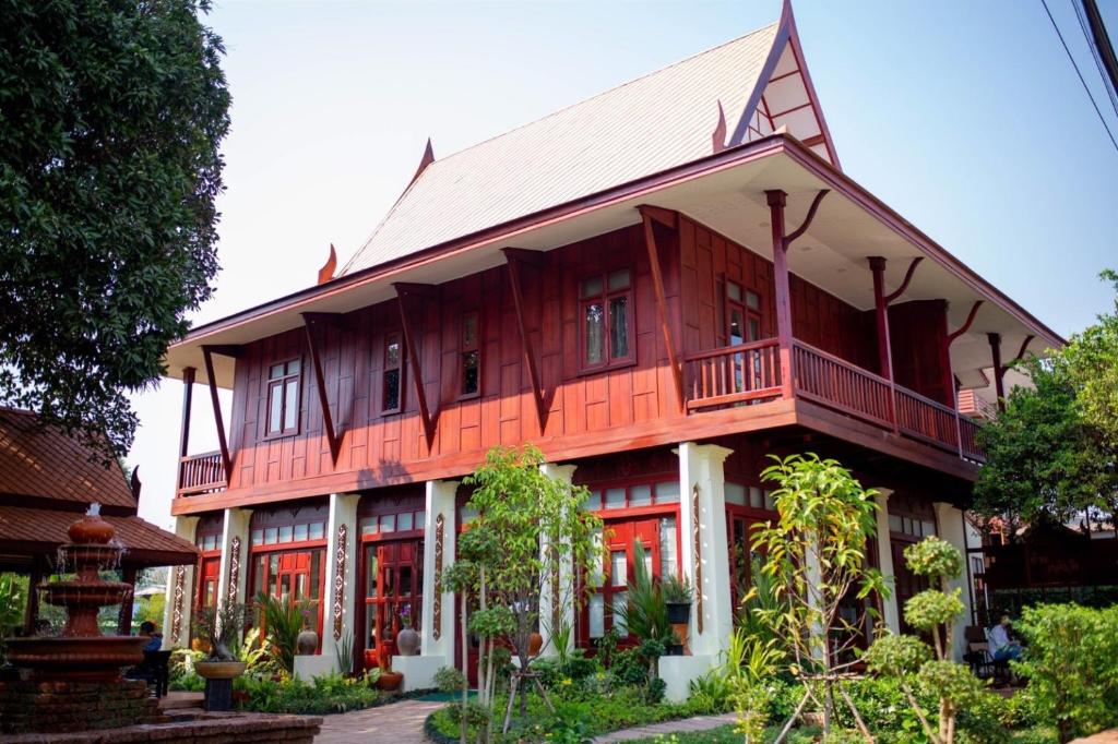 une grande maison en bois avec un gambrel dans l'établissement Baan Lhang Wangh บ้านหลังวัง, à Phitsanulok
