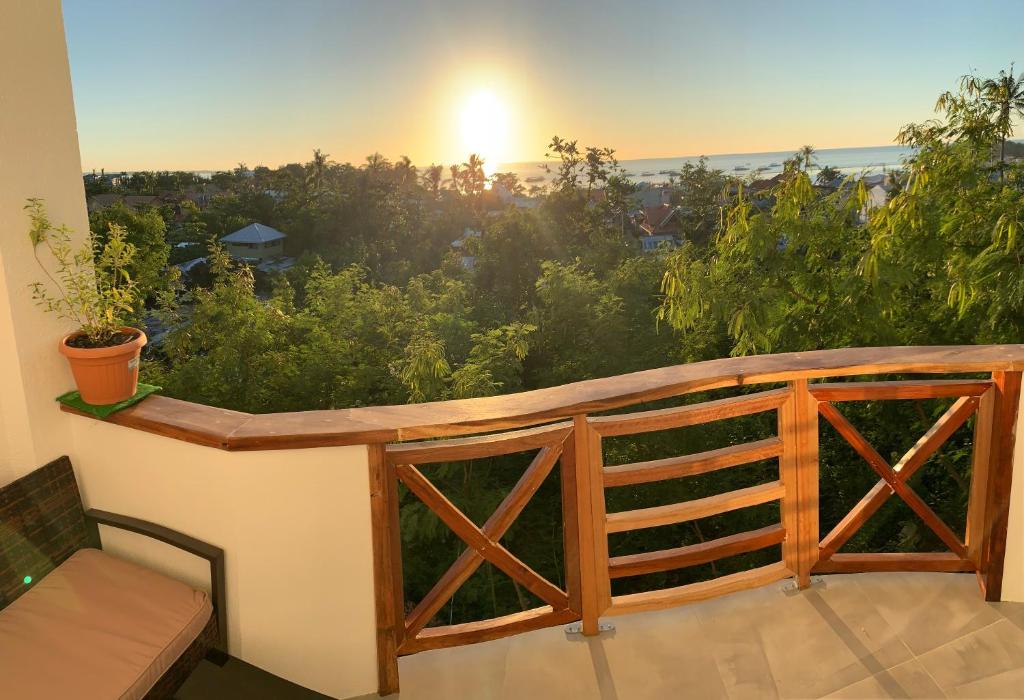 a balcony with a wooden railing and a sunset at Crown Malapascua in Malapascua Island
