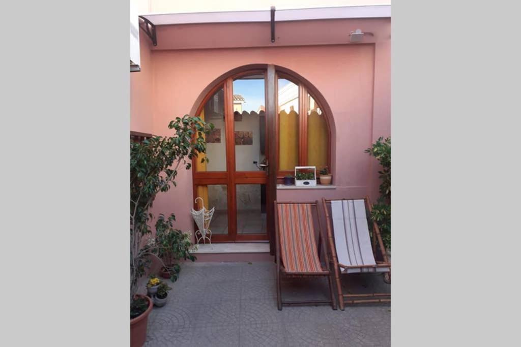 a pink house with a door and a chair at CASA MILENA in Settimo San Pietro