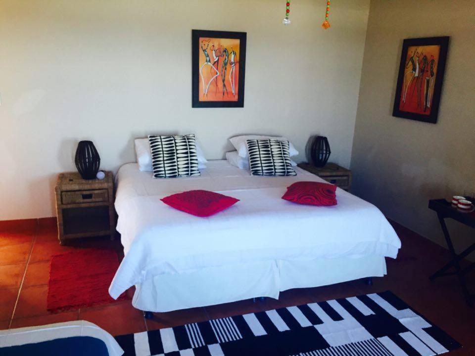 Un dormitorio con una cama blanca con almohadas rojas. en Anchorage B&B, en Elysium