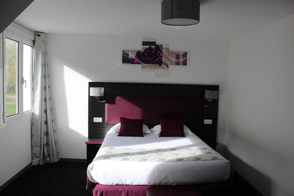 um quarto com uma cama com uma cabeceira rosa em The Originals City Hôtel, Aéroport Beauvais (ex: Inter-Hotel) em Beauvais