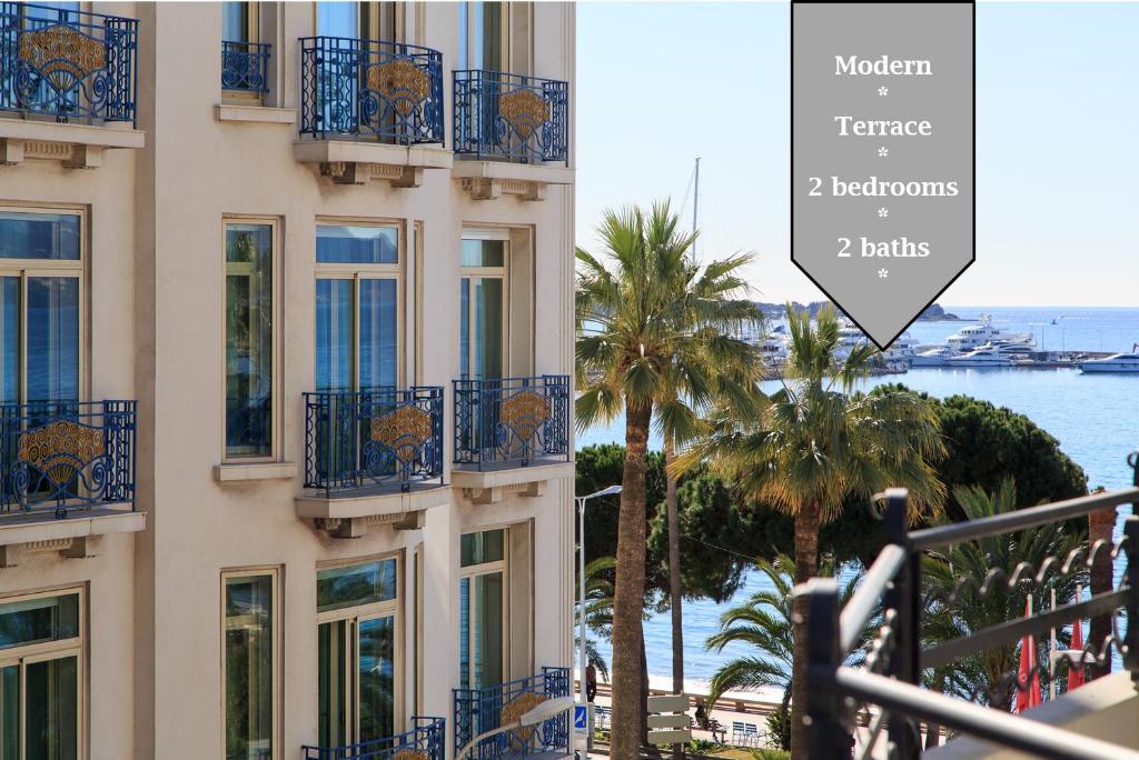 un bâtiment avec des balcons bleus, des palmiers et l'océan dans l'établissement MARTINEZ AREA: NEW 2BEDS/2BATHS, à Cannes