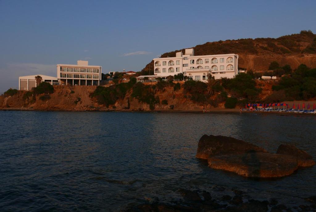 een groot gebouw bovenop een heuvel naast een waterlichaam bij E.J. Pyrgos Bay Hotel in Kato Pyrgos