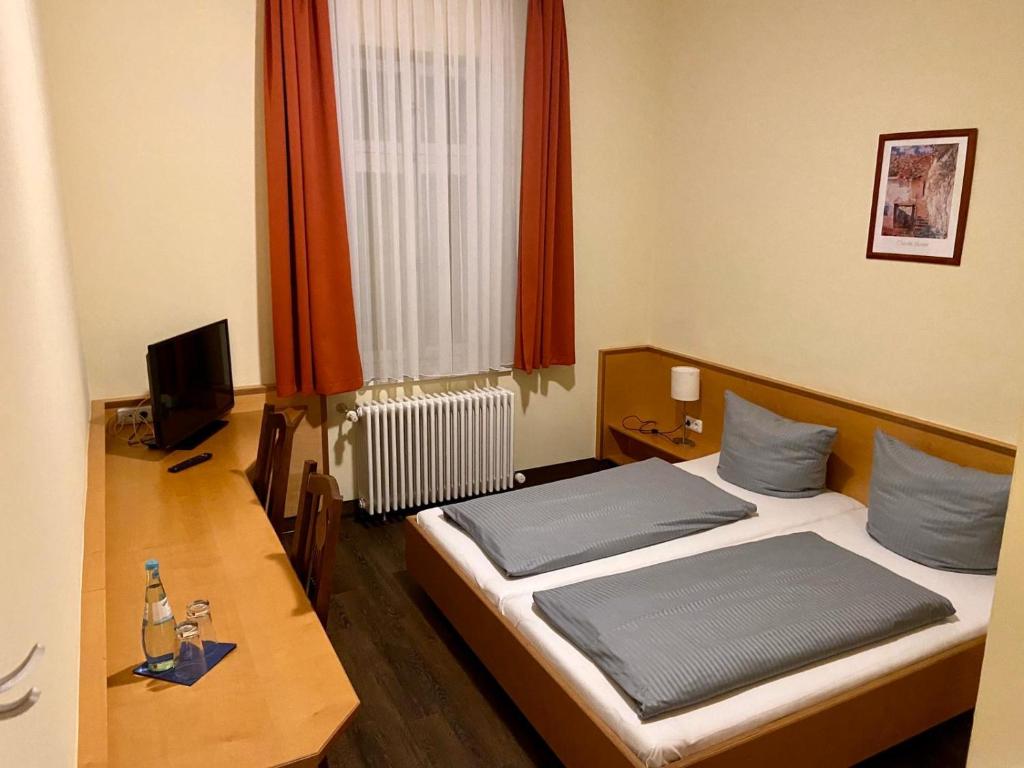 a bedroom with a bed and a desk and a television at Münchner Hofbräu Coburg in Coburg