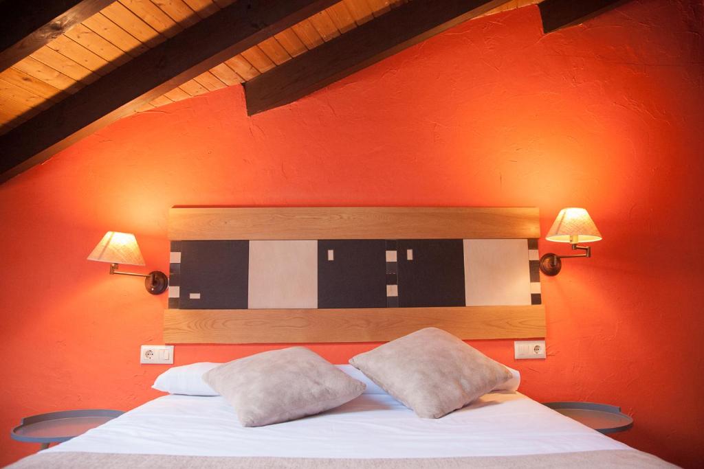 a bedroom with an orange wall with a bed with two pillows at Los Picos in Porrúa