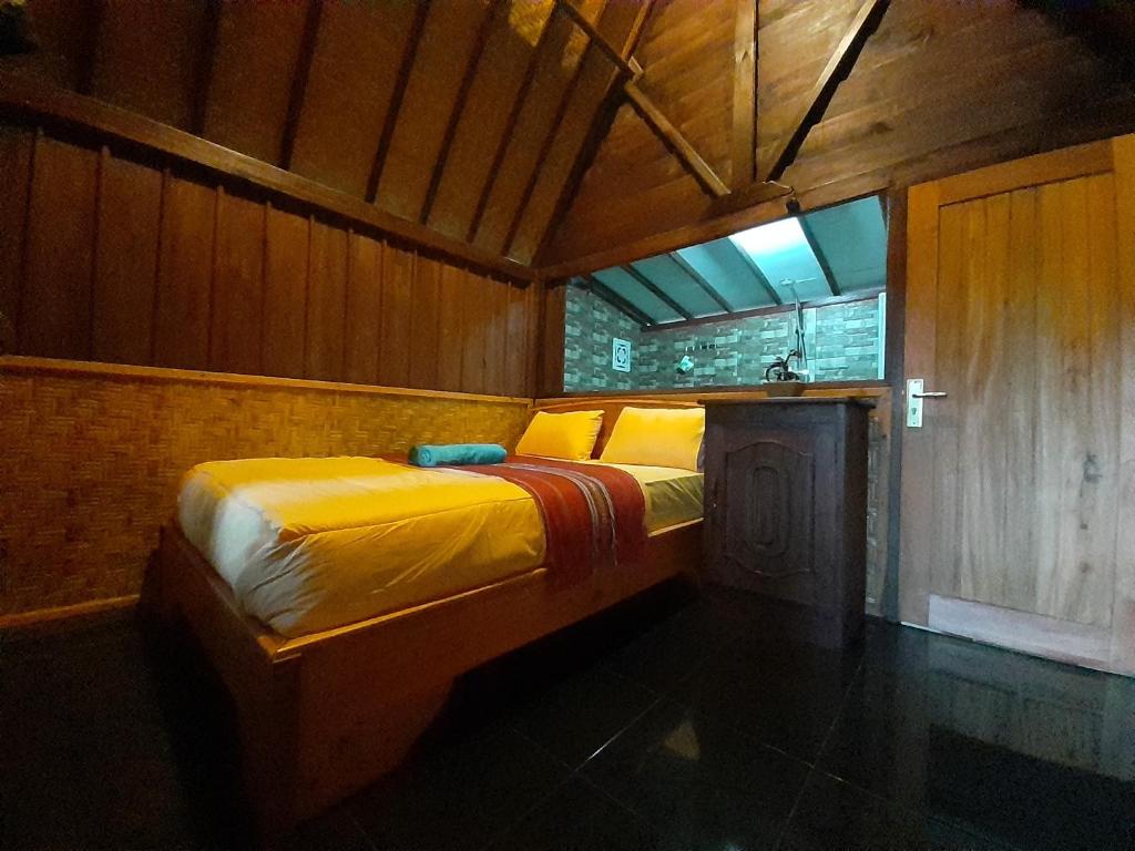 1 dormitorio con 1 cama en una habitación de madera en Tetebatu Valley Bungalows, en Tetebatu