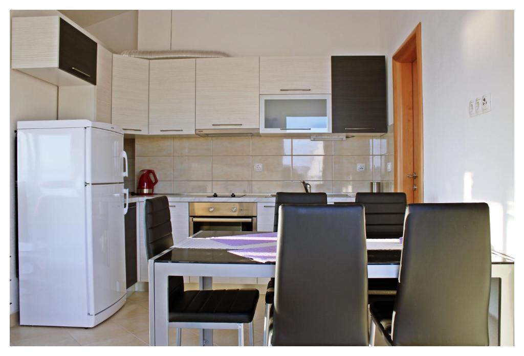 cocina con mesa, sillas y nevera blanca en Apartments Dirsi, en Trogir