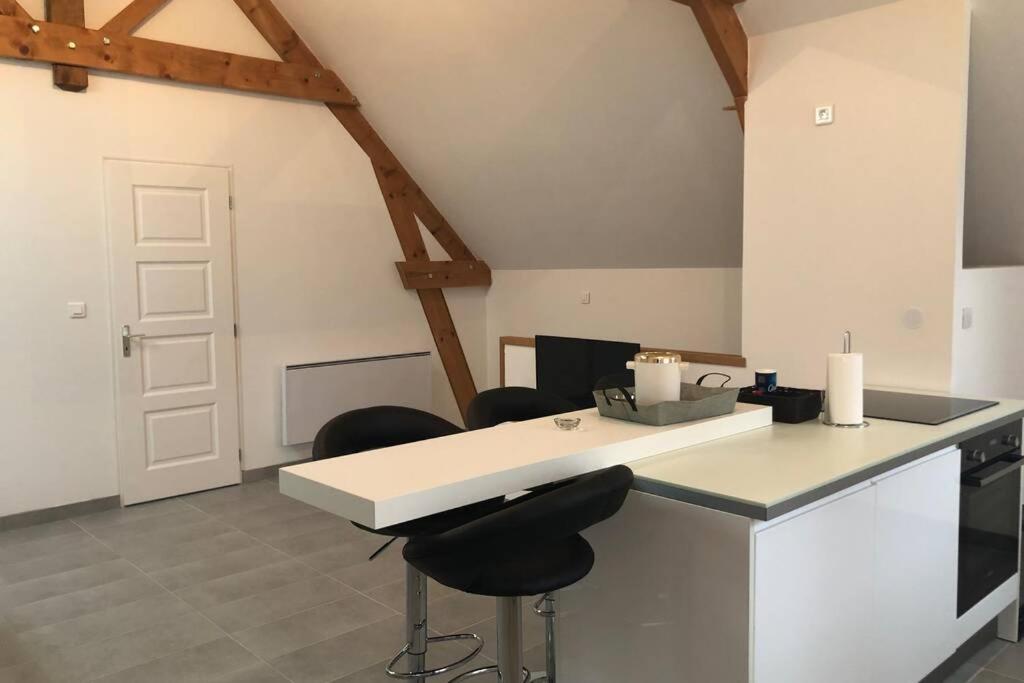 una cucina con un bancone e sgabelli in una stanza di la petite loge ad Ay