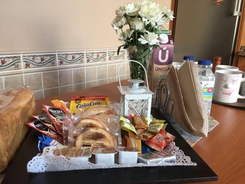 una mesa con una bandeja de comida y un jarrón con flores en Pisos Turísticos Muxía -Teresa Barros, en Muxía