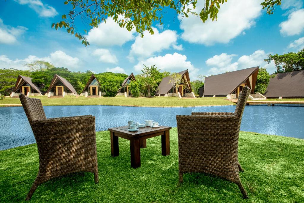 two chairs and a table in front of a lake at Liyya Water Villas in Dambulla