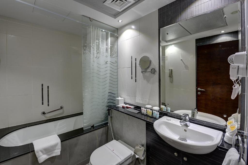 a bathroom with a sink and a toilet and a mirror at Marina View Deluxe Hotel Apartment in Dubai