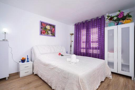Guest House Lana Denia في دينيا: غرفة نوم بسرير أبيض وستائر أرجوانية