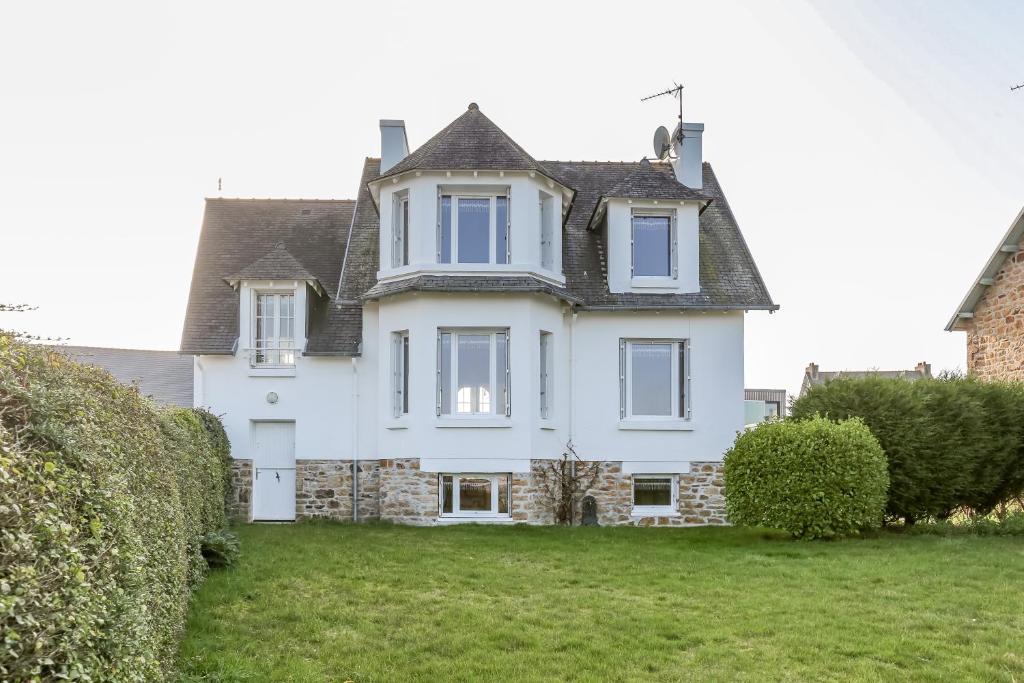 ein großes weißes Haus mit grauem Dach in der Unterkunft CABESTAN - Maison de famille au coeur du bourg - Vue Mer in Carantec