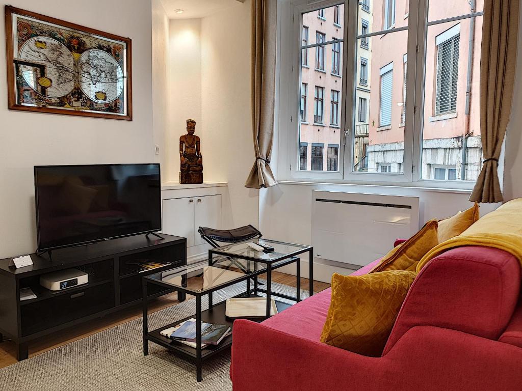 a living room with a red couch and a tv at Le Tisserand by Cocoonr in Lyon