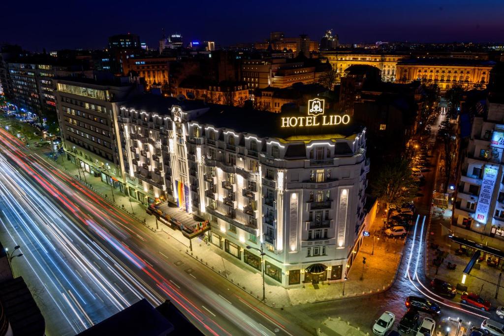 un edificio con un hotel lidocaína encima de él por la noche en Hotel Lido by Phoenicia en Bucarest