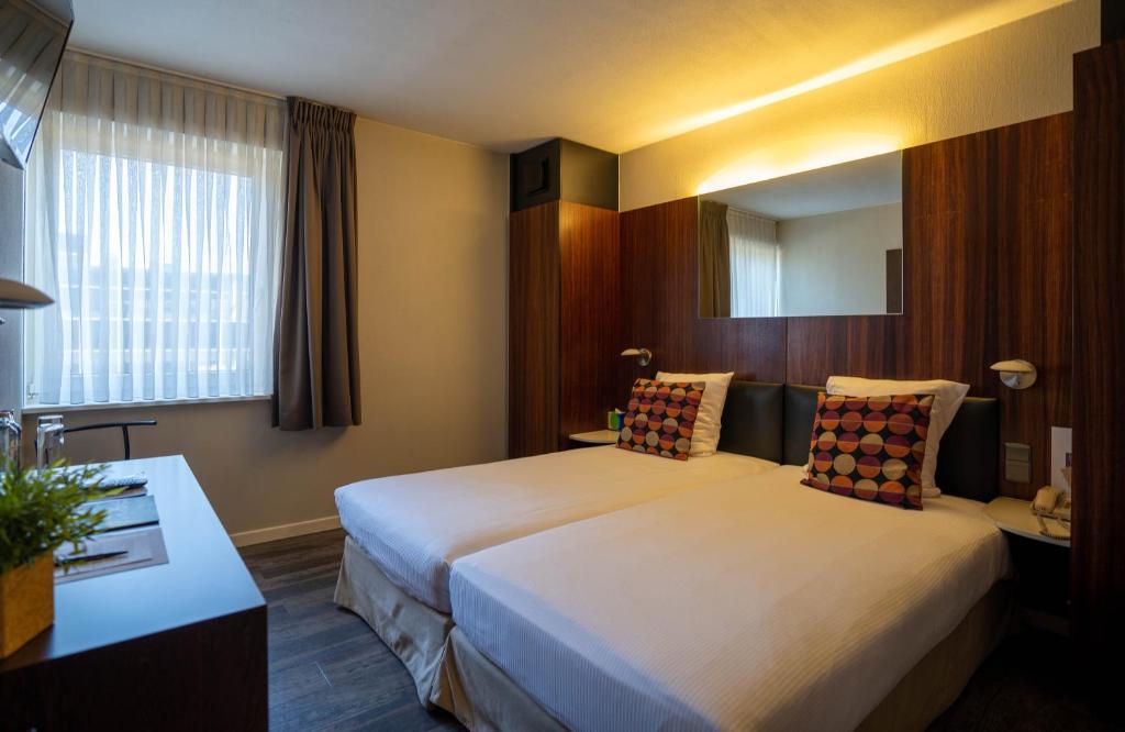 een hotelkamer met 2 bedden en een spiegel bij Gosset Hotel in Groot-Bijgaarden