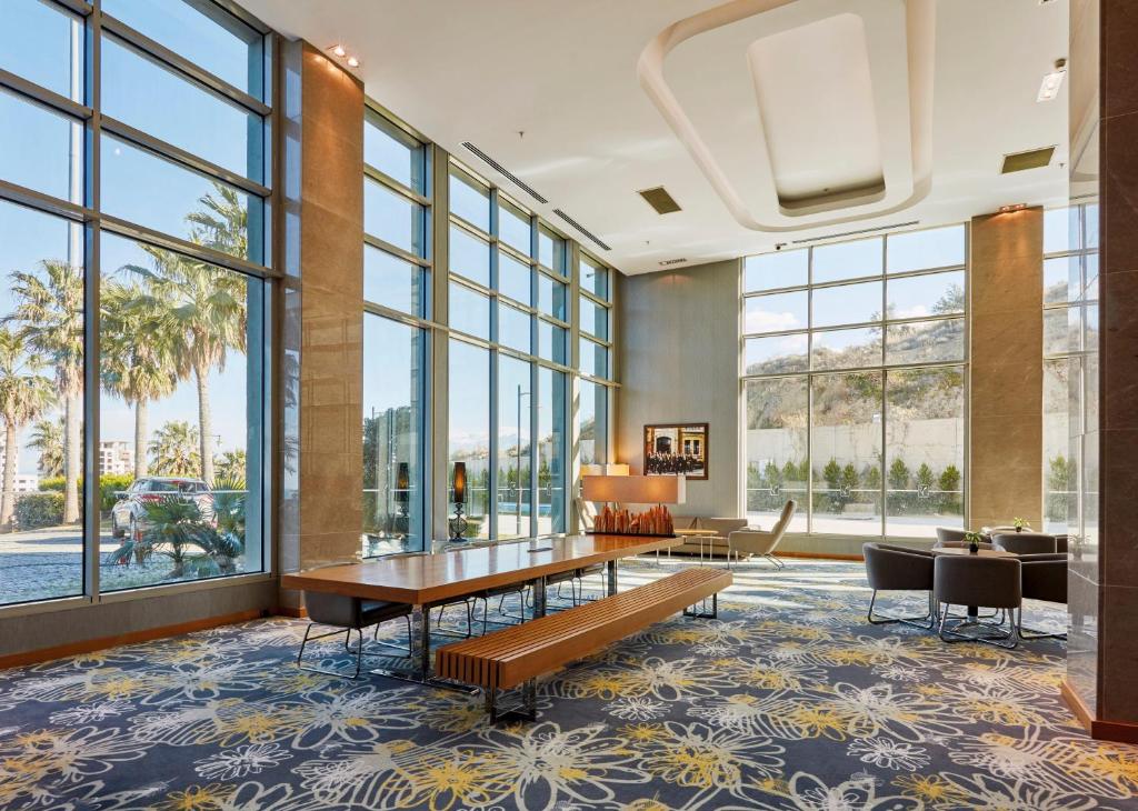 a lobby with a table and chairs and large windows at Anemon Iskenderun Hotel in İskenderun