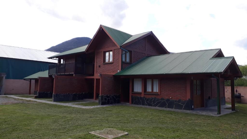 a brown brick house with a green roof at Lago Puelo Departamentos Turisticos in Lago Puelo