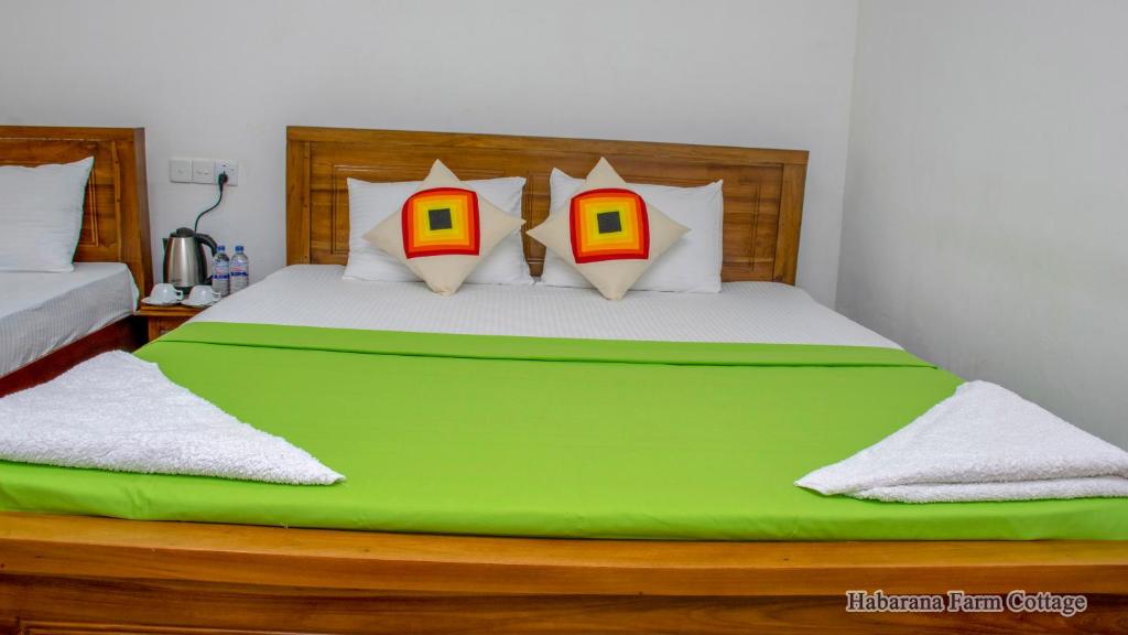 ein Schlafzimmer mit einem großen grünen Bett mit vier Kissen in der Unterkunft Habarana Farm Cottage in Avudangawa