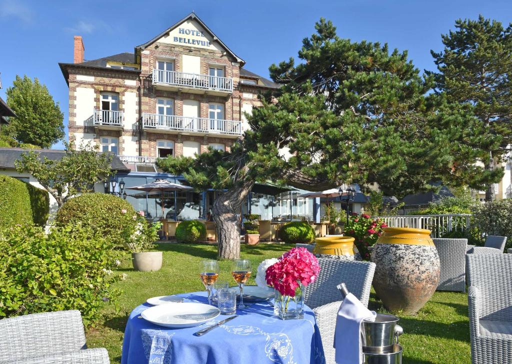 uma mesa azul com copos de vinho e flores em Hotel Bellevue em Villerville
