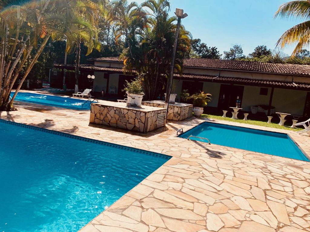 una piscina junto a una casa con palmeras en Boiçucanga Completo à Beira Mar en Boicucanga