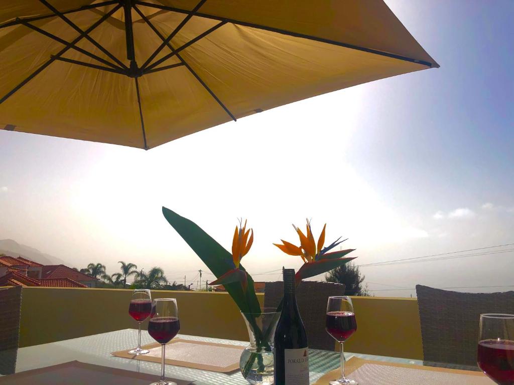 a table with wine glasses and an umbrella at Casa do Manuel Maria in Estreito da Calheta