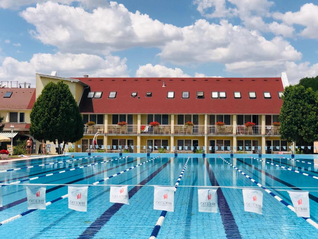 a large swimming pool with a building in the background at Hét Vezér Apartmanhotel in Komárom